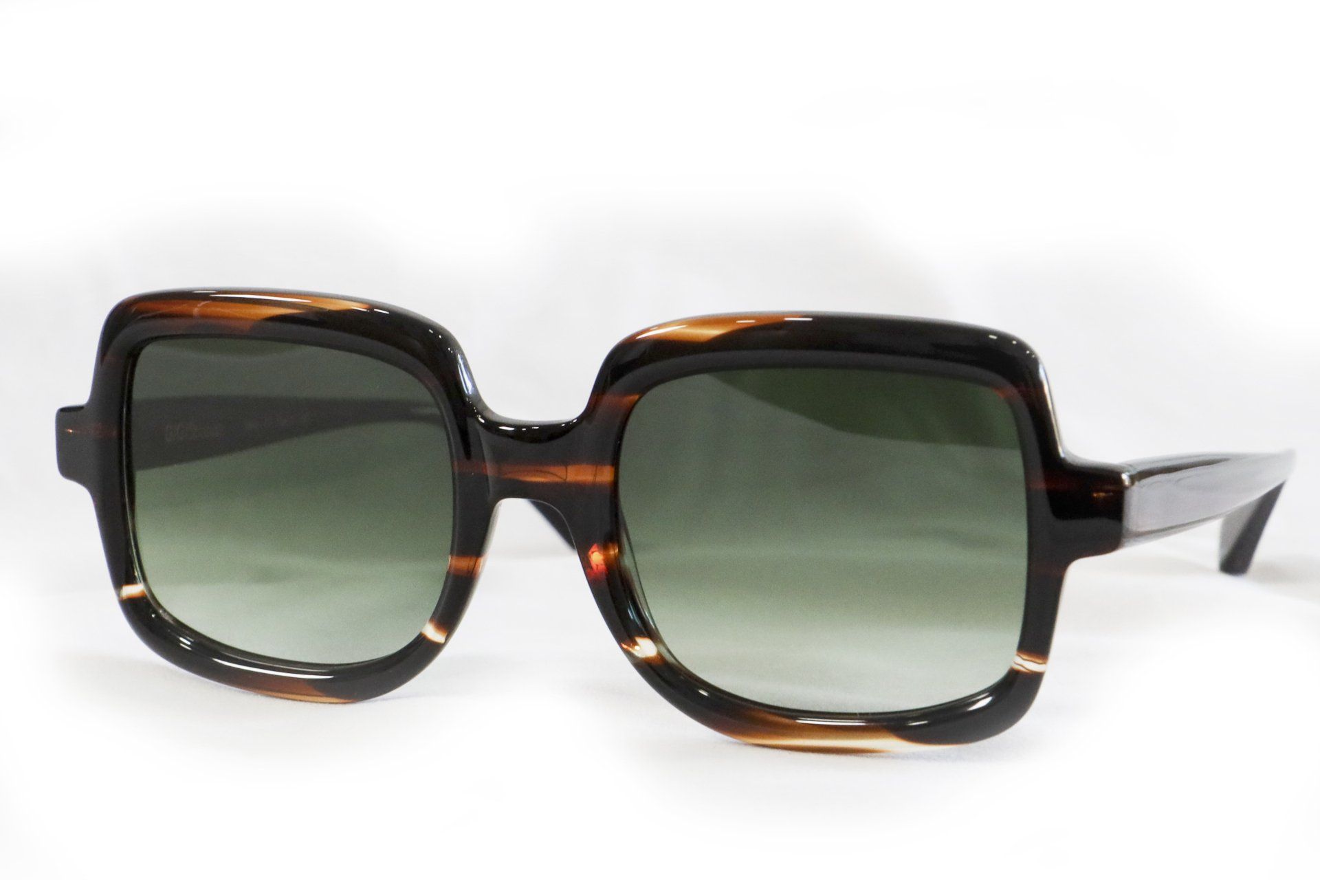 Occhiali da sole color tartaruga marrone con montatura quadrata e lenti verdi.