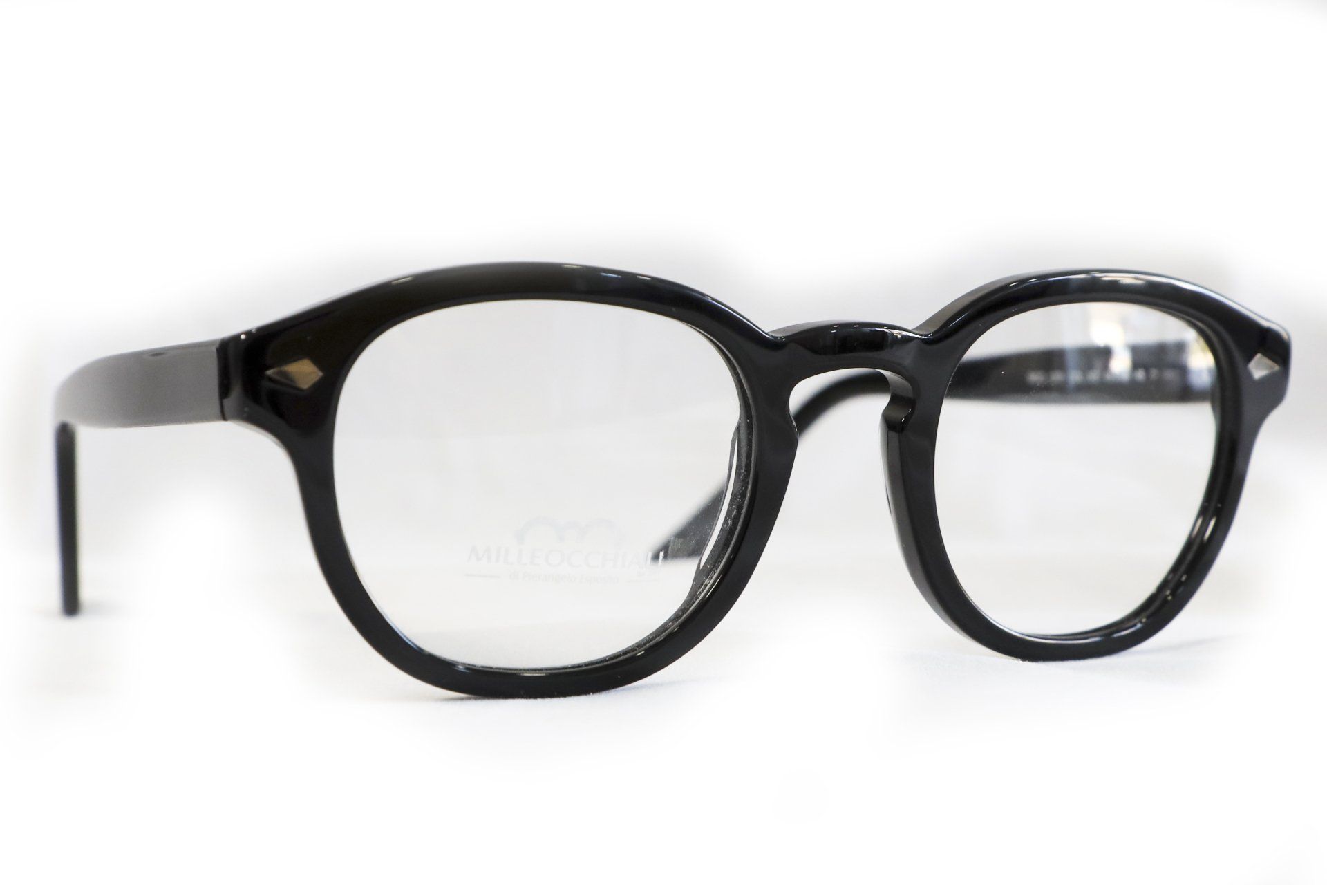 Occhiali da vista neri con montatura rotonda su sfondo bianco. Dettaglio di diamanti sulle aste.