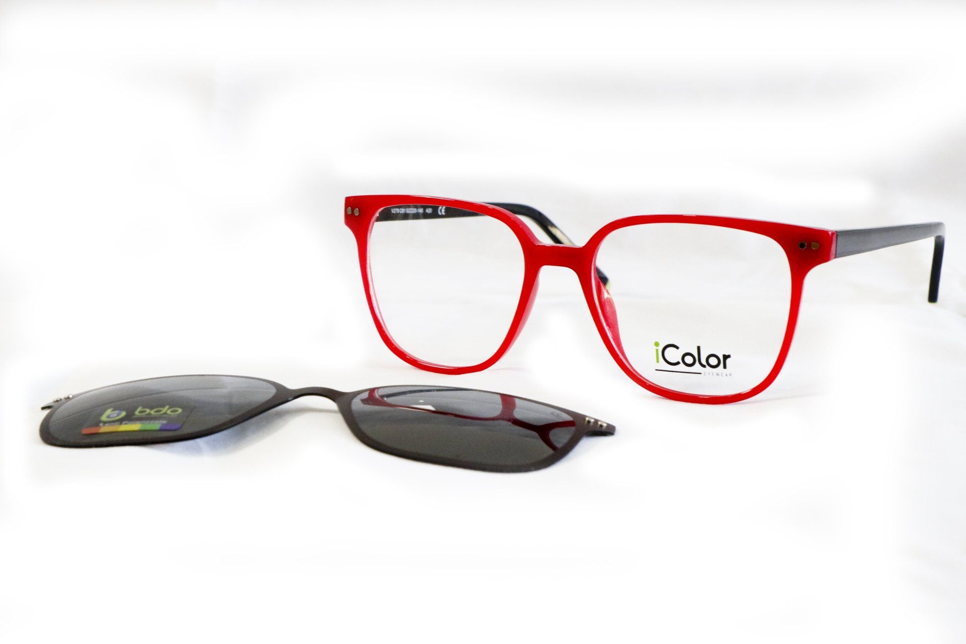 Occhiali da vista rossi con attacco magnetico per occhiali da sole su sfondo bianco.