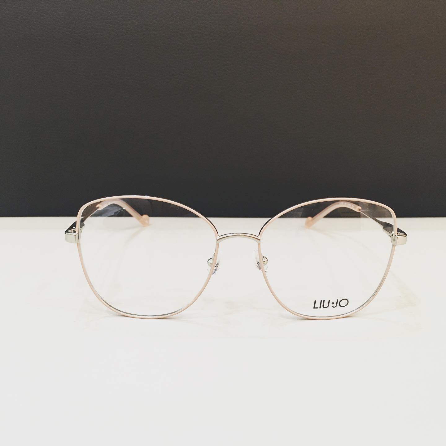 Occhiali da vista con montatura dorata e lenti rotonde; logo