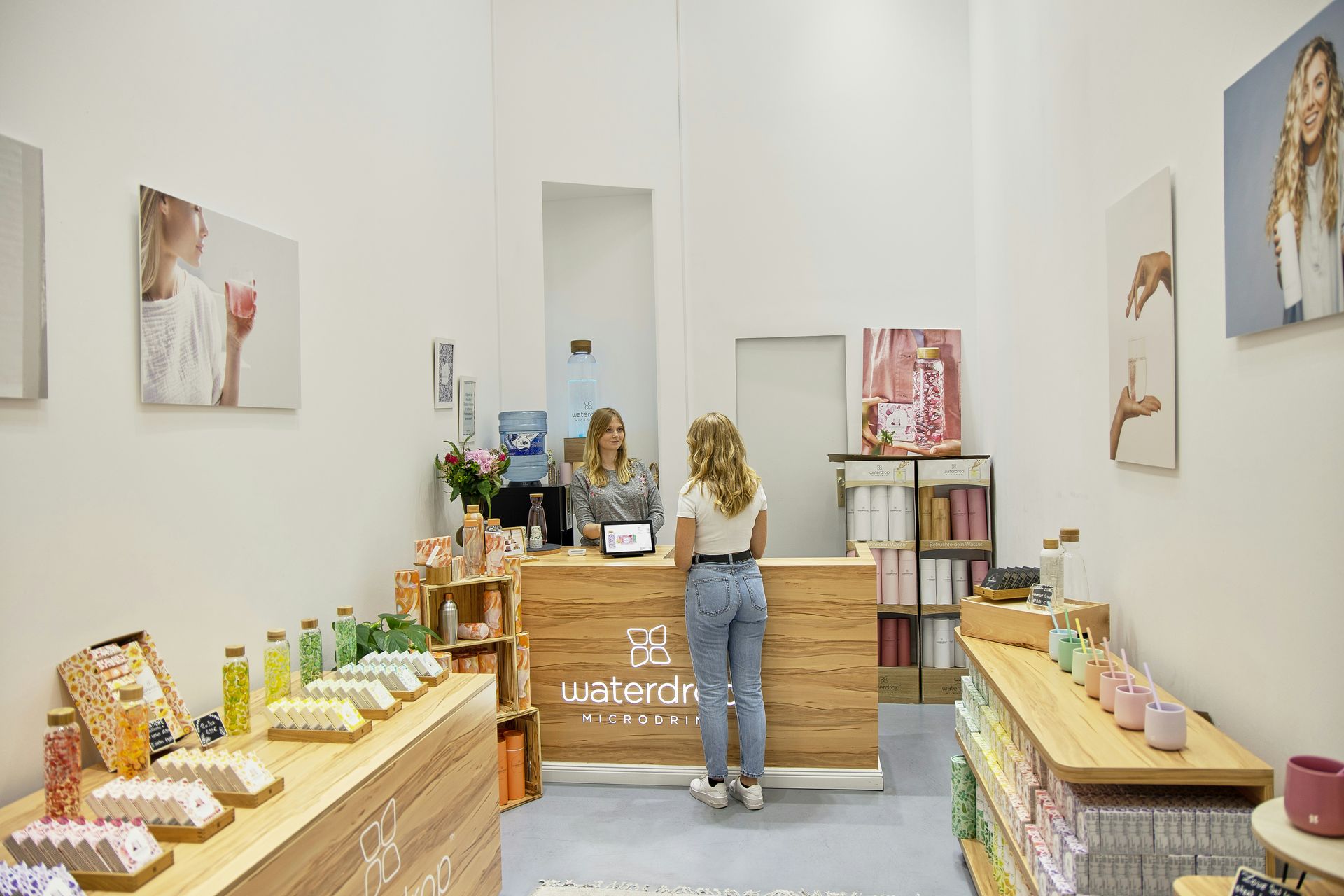A customer at a shop counter, with a clerk. Display shelves with products, artwork on walls.