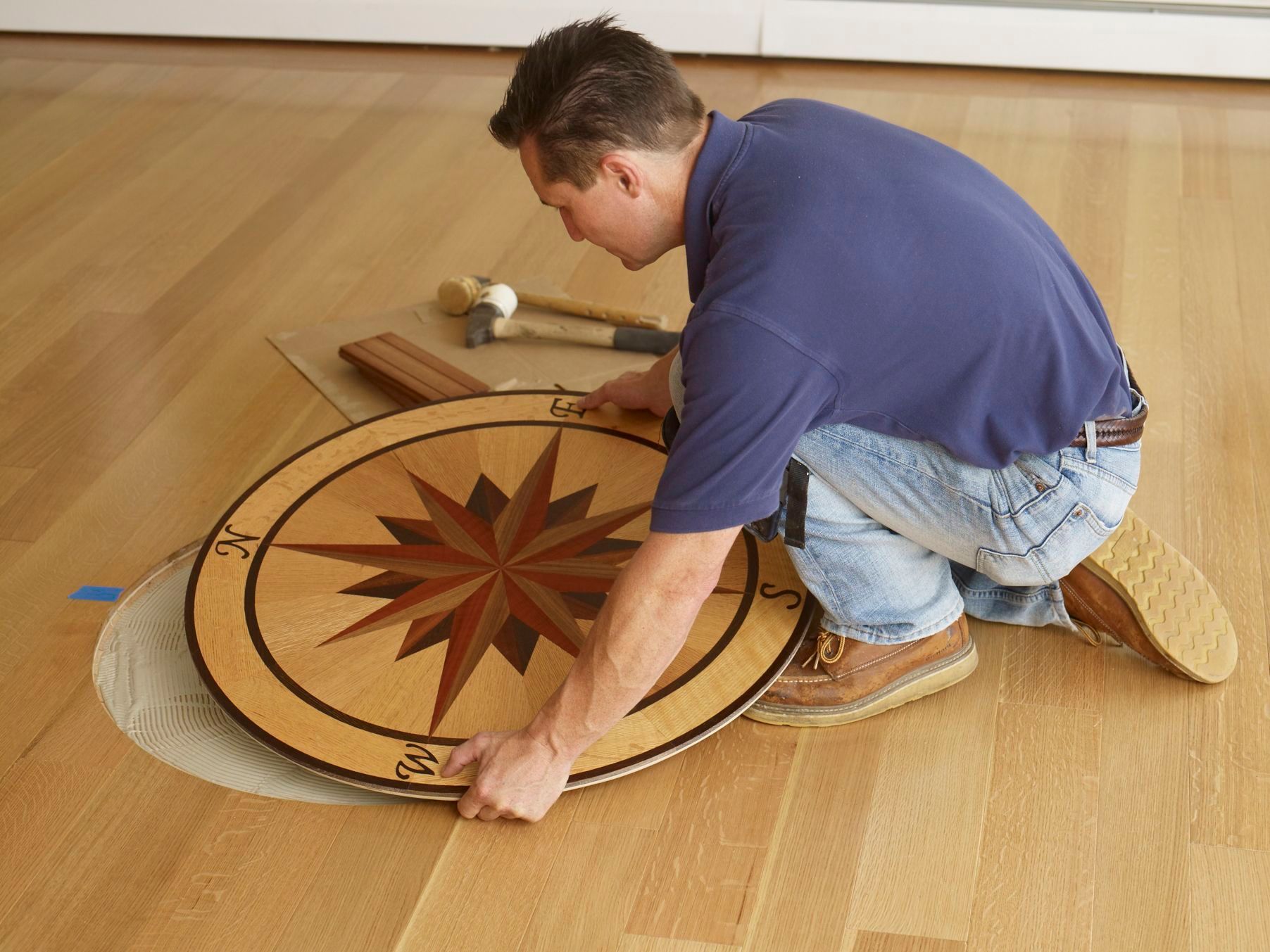 A man is installing a wooden compass on the floor