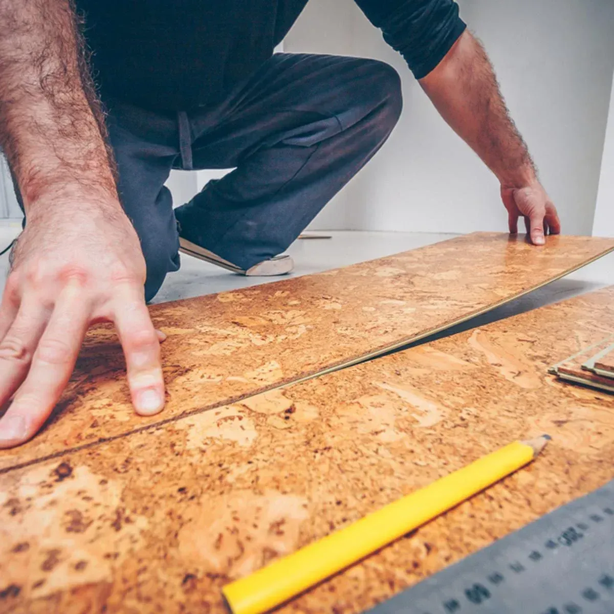 A man is measuring a piece of cork flooring.