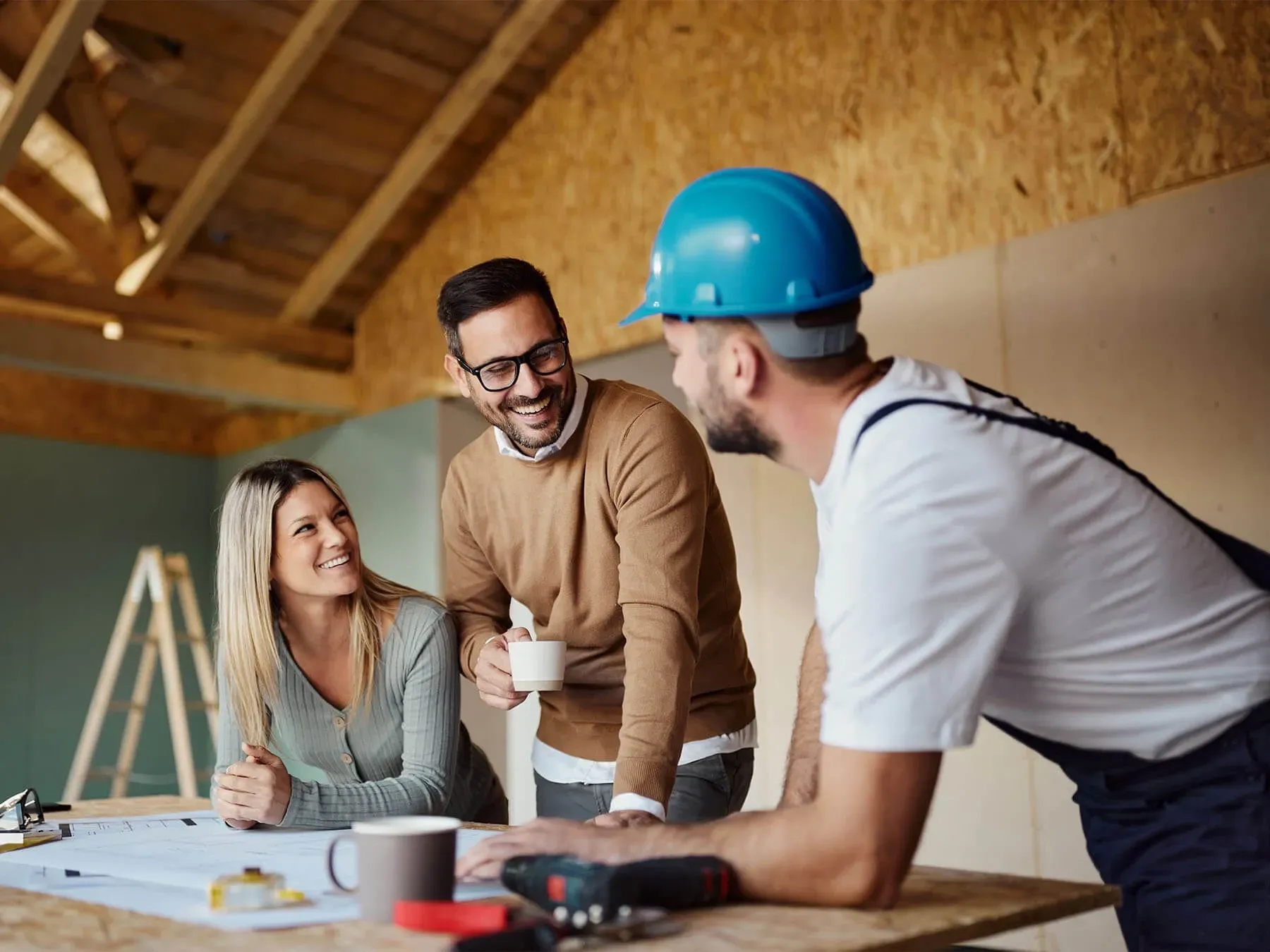 A man in a hard hat is talking to a woman and a man.