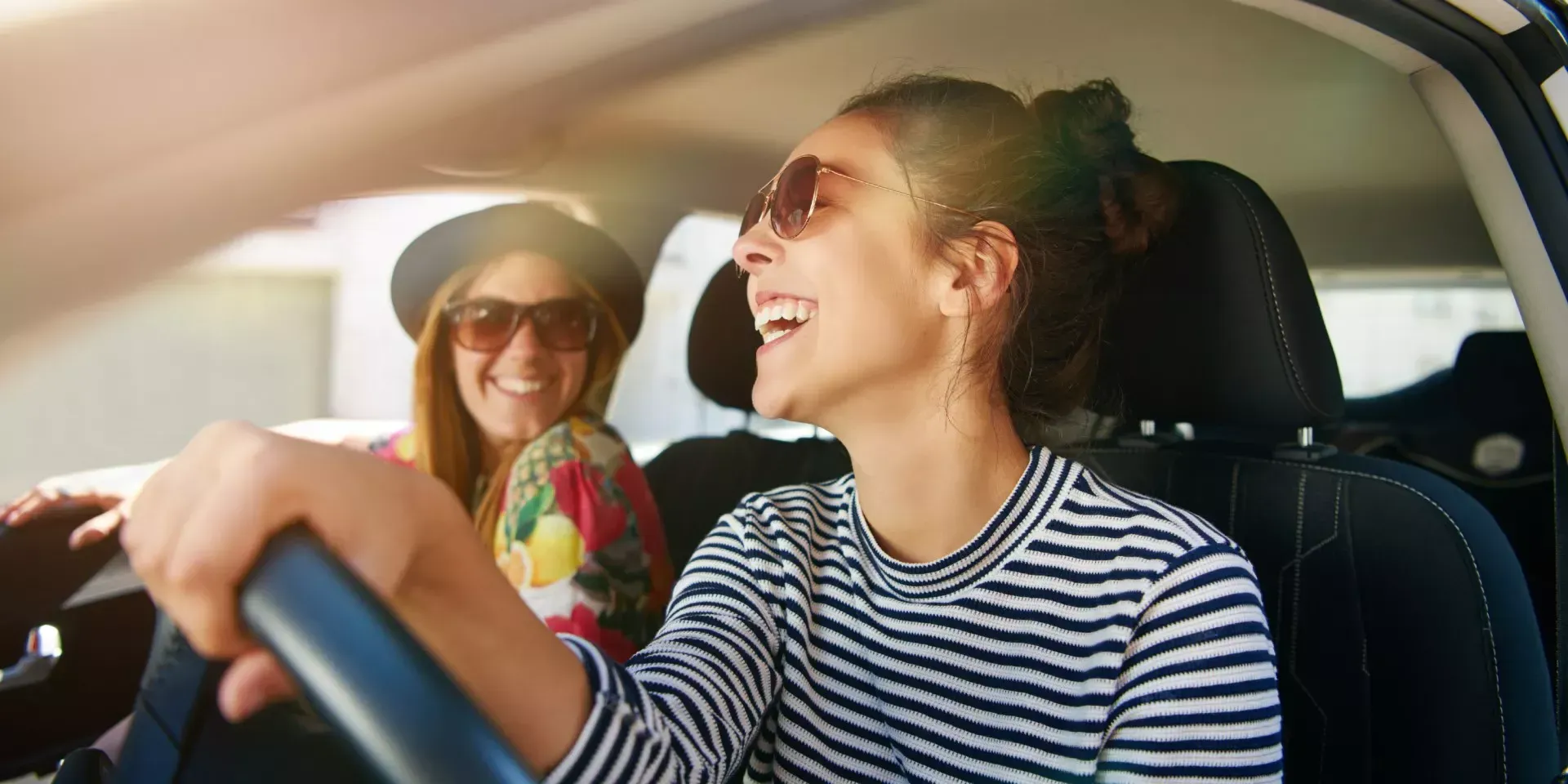 SUV vermelho estacionado em paralelepípedos com o pôr do sol ao fundo.