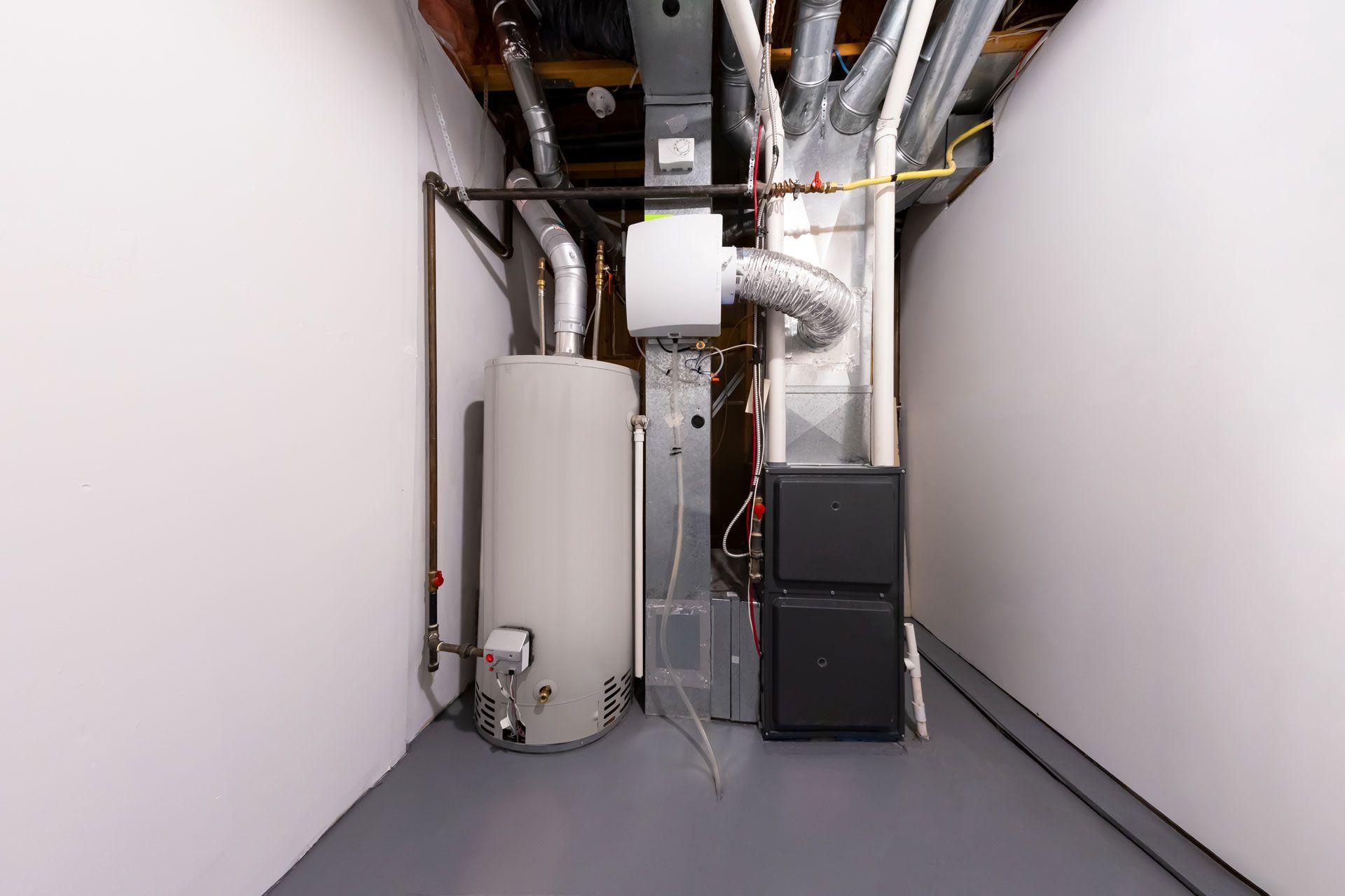 Water heater, furnace, and ductwork in a freshly painted basement.