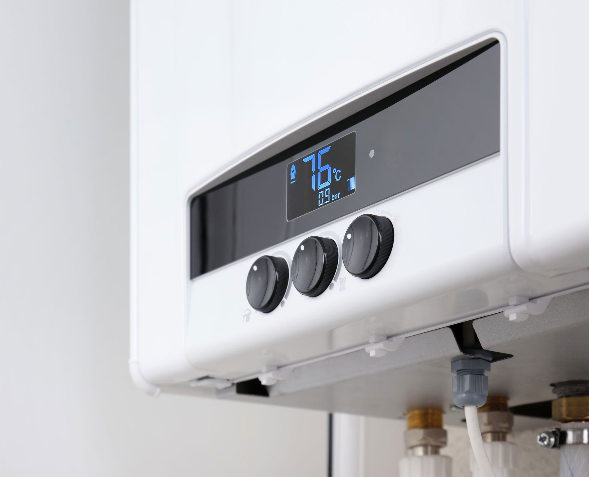 White wall-mounted boiler with digital display showing 76 degrees. Three black knobs below display.