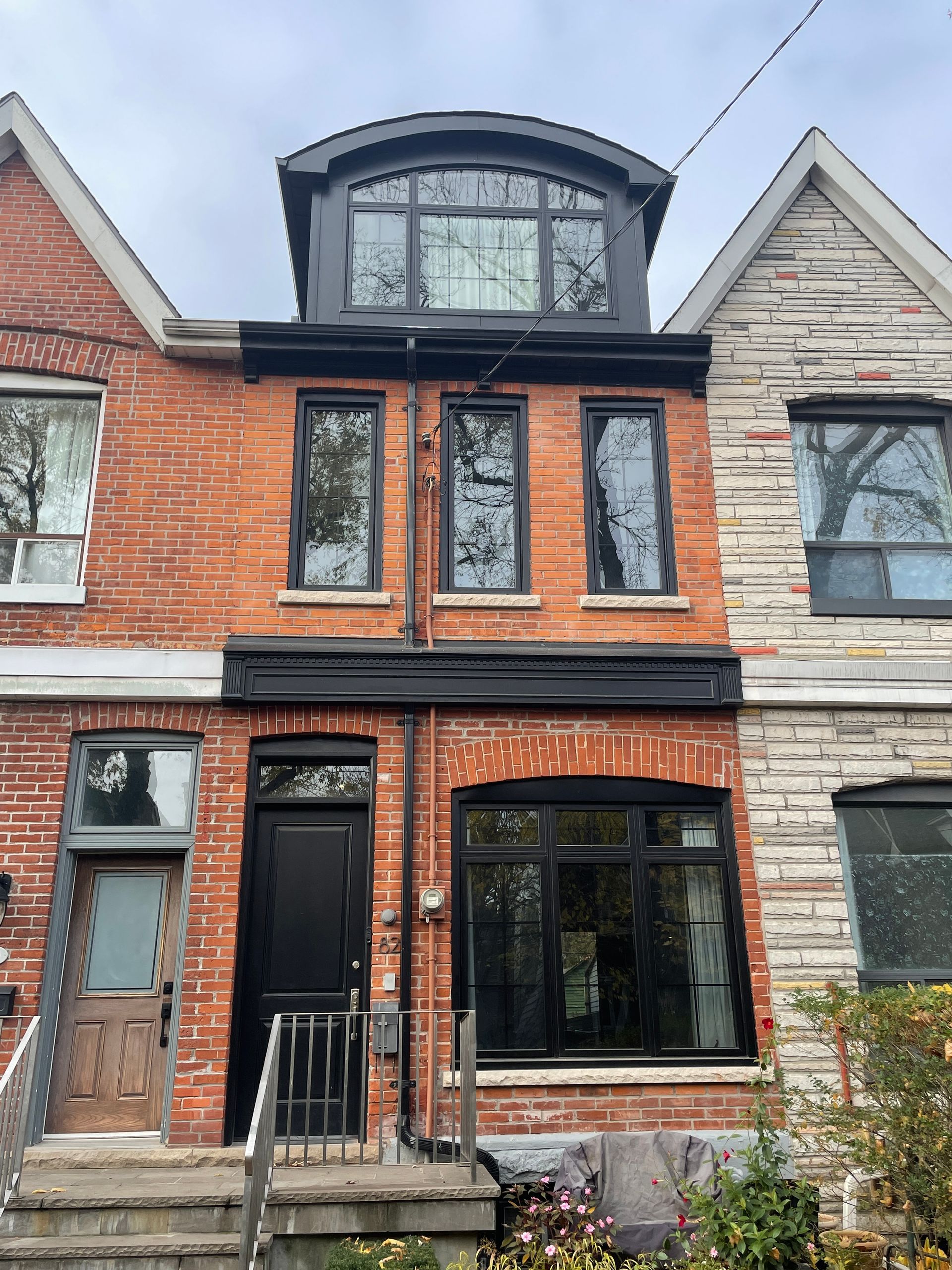 A brick and stone house with a black door and windows.