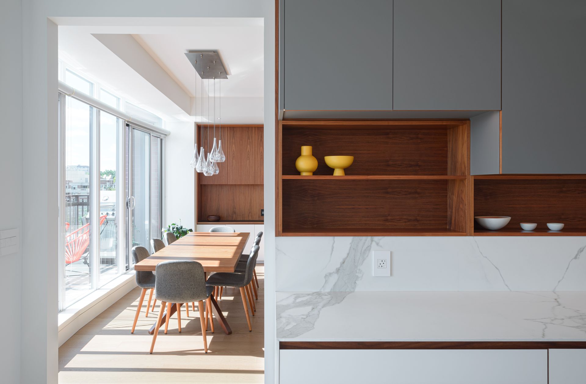 A dining room with a table and chairs and a shelf with vases on it.