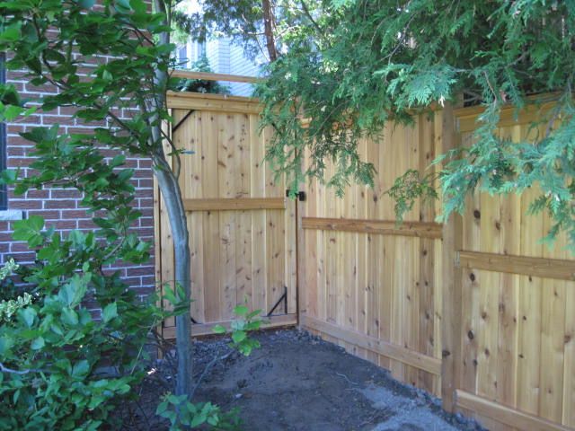 A wooden fence with a gate in front of a brick house.