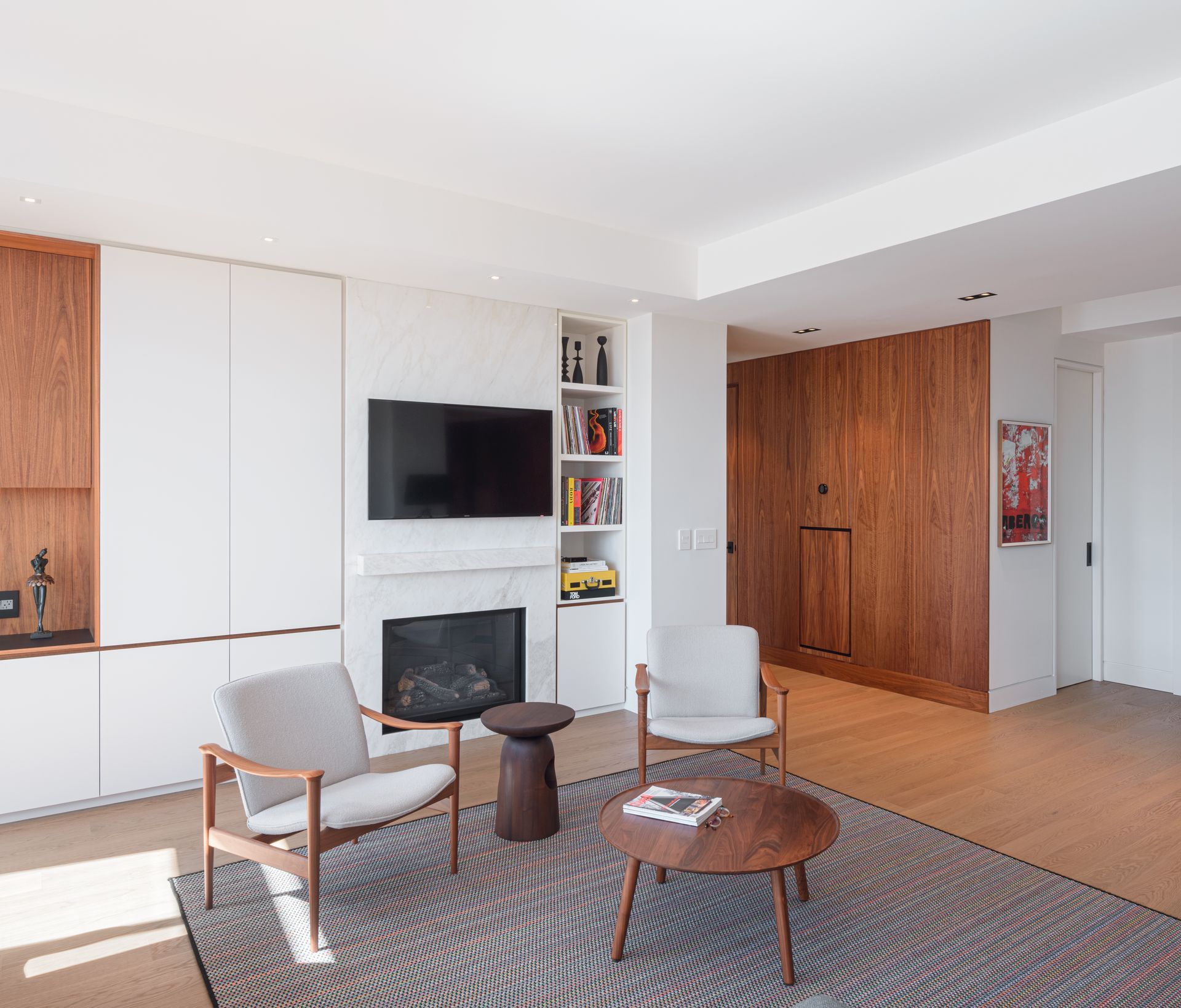 A living room with a fireplace , chairs , a table and a flat screen tv.