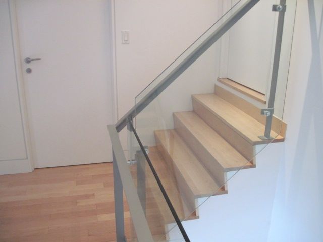 A staircase with a glass railing and wooden steps