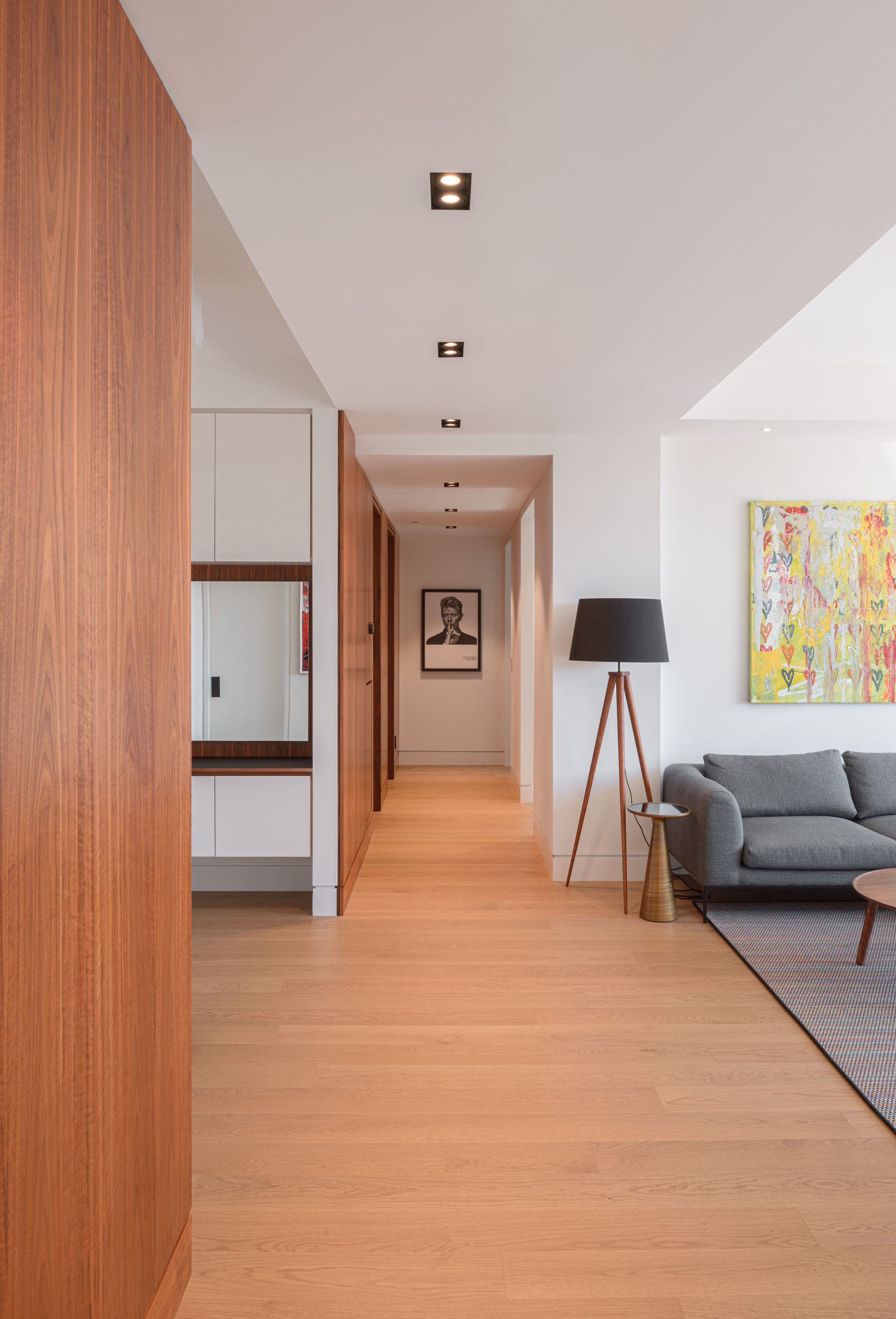A living room with a couch and a lamp in a hallway.