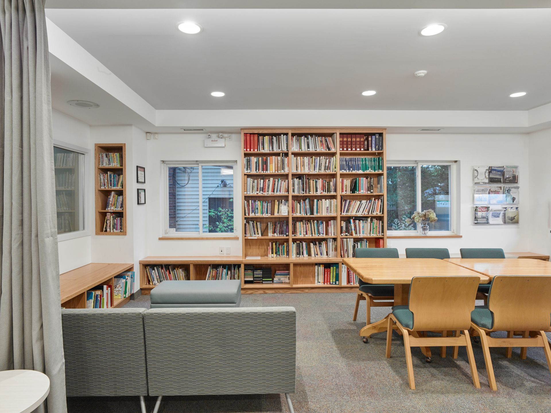 A living room with a couch , table , chairs and bookshelves.
