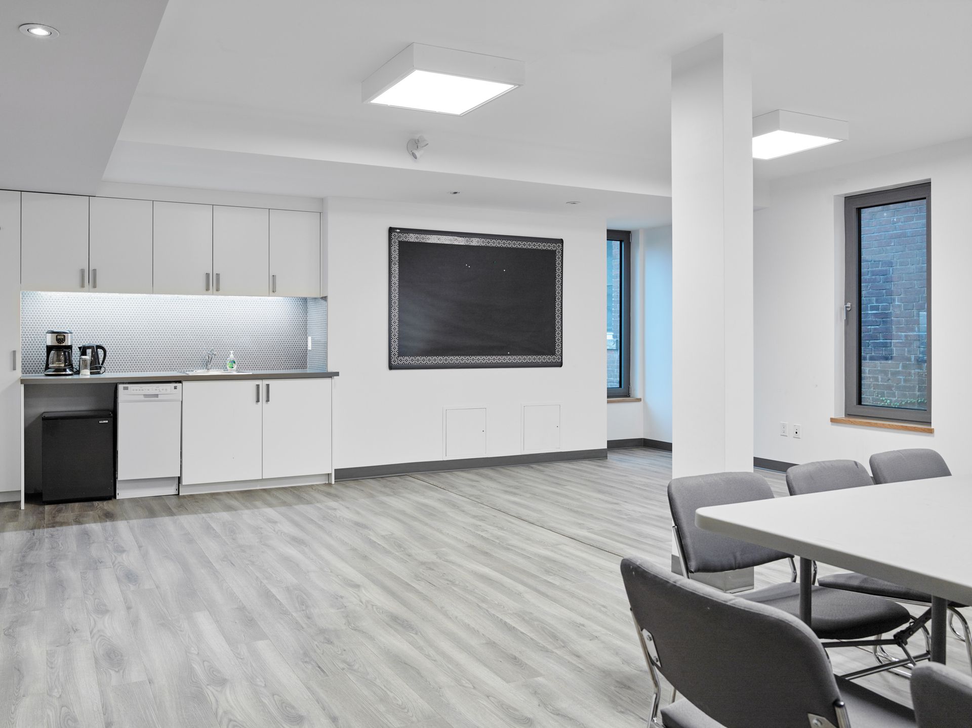 A large room with a table and chairs and a blackboard on the wall.