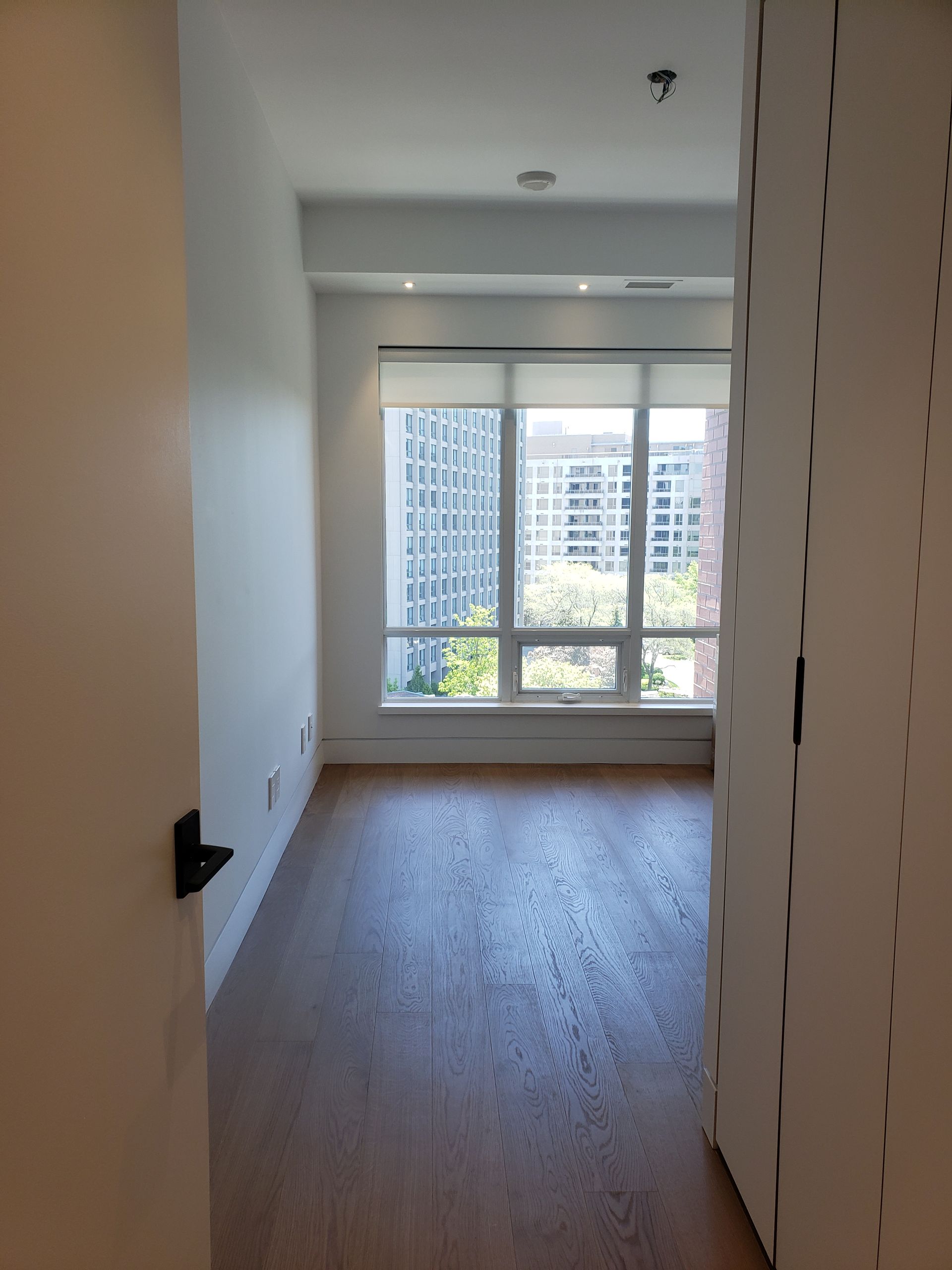 An empty room with hardwood floors and a large window
