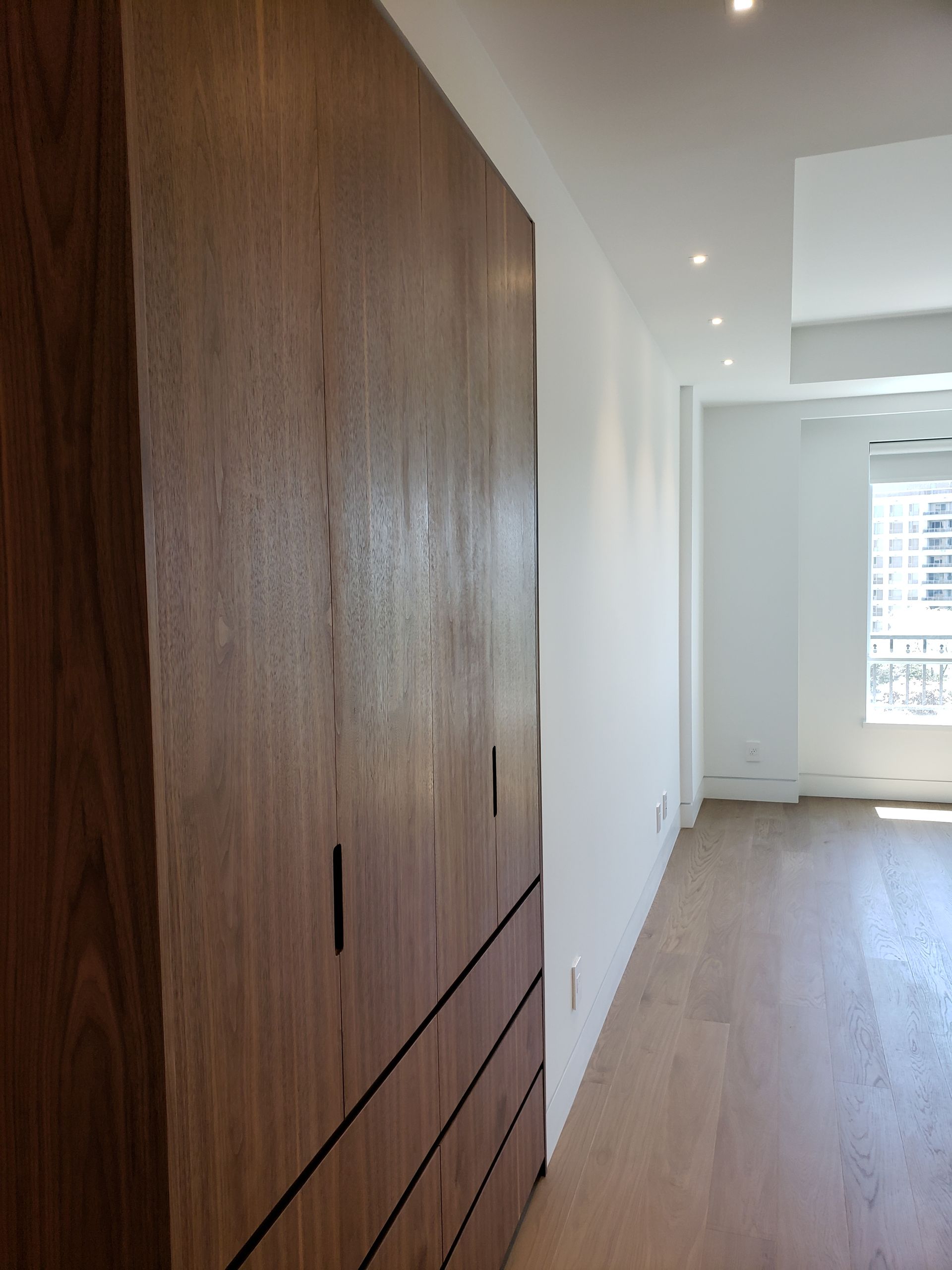 A hallway with wooden cabinets and a window