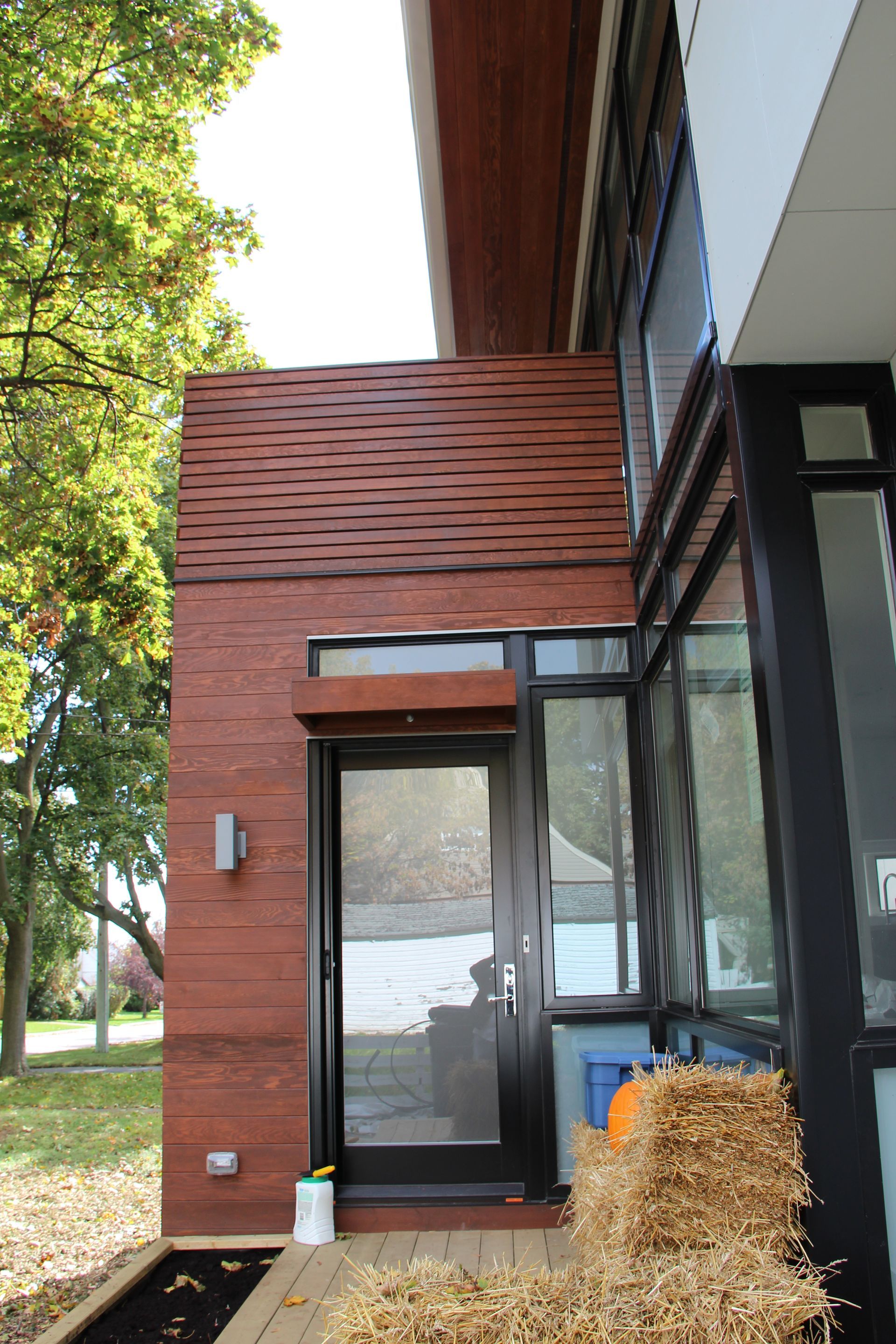 The front door of a house with a hay bale in front of it.