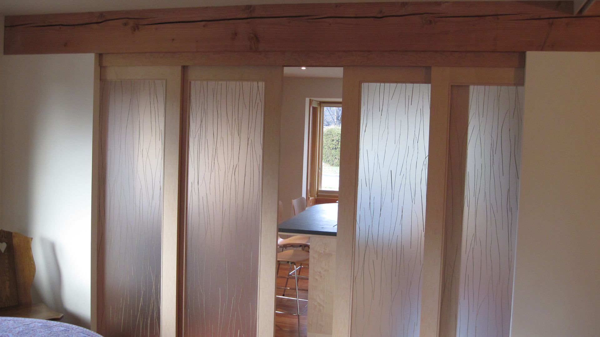 A bedroom with sliding glass doors leading to a kitchen