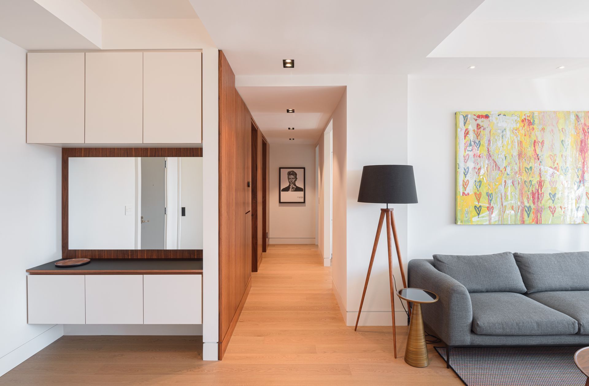 A living room with a couch , lamp , mirror and painting on the wall.