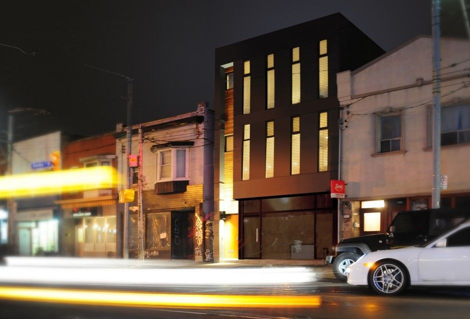 A white car is parked in front of a building at night