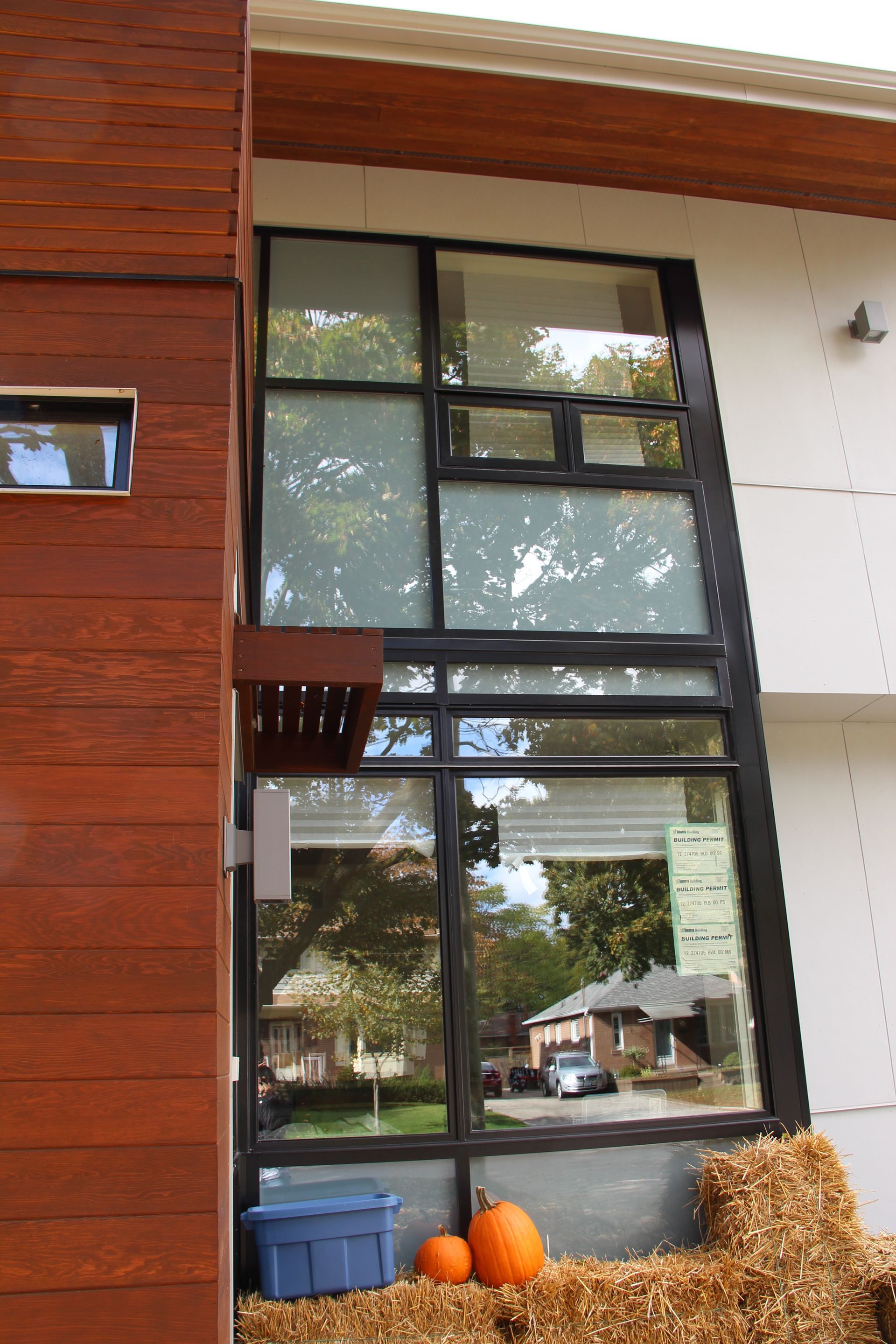 A house with a large window and hay bales in front of it