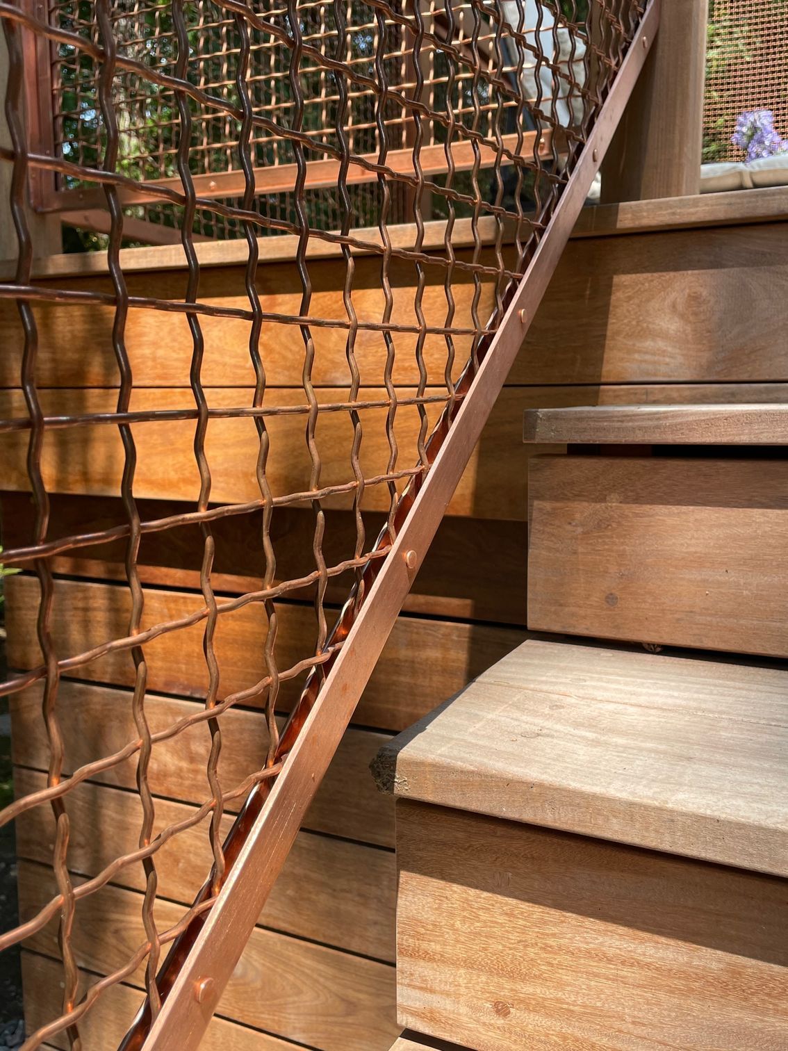 A close up of a wooden staircase with a copper railing.