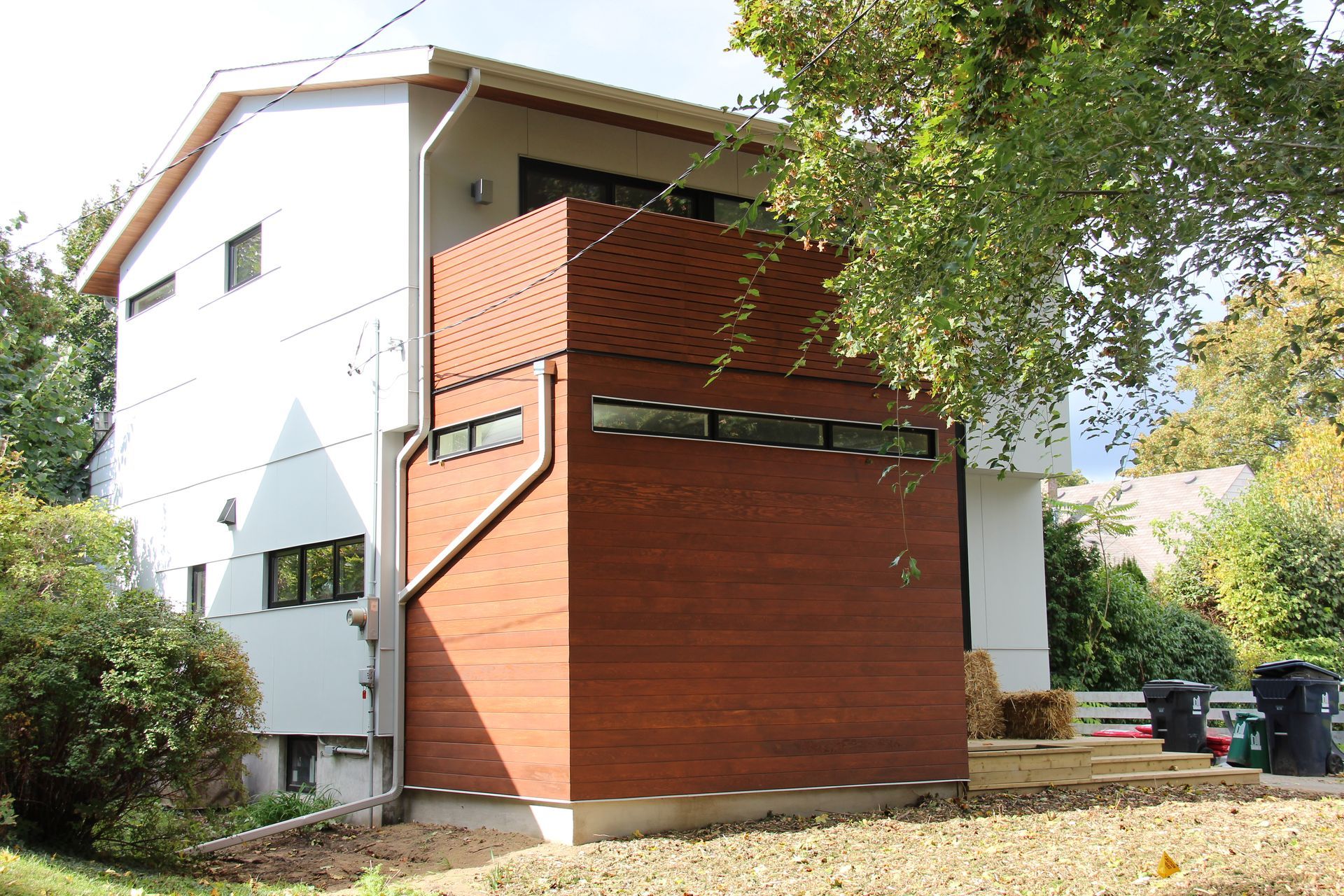 A white house with a red brick wall and a balcony