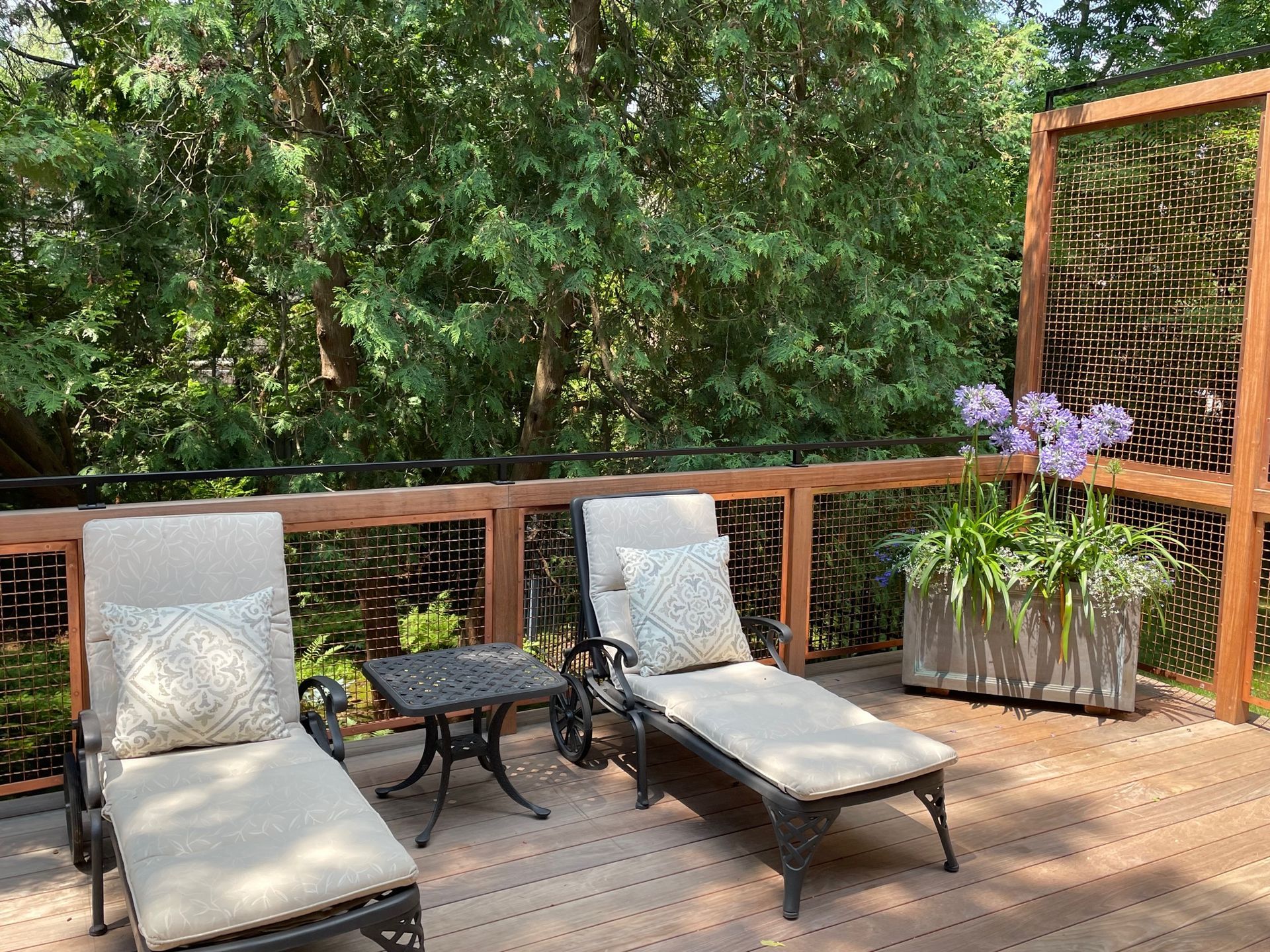 Two lounge chairs are sitting on a wooden deck next to a table.