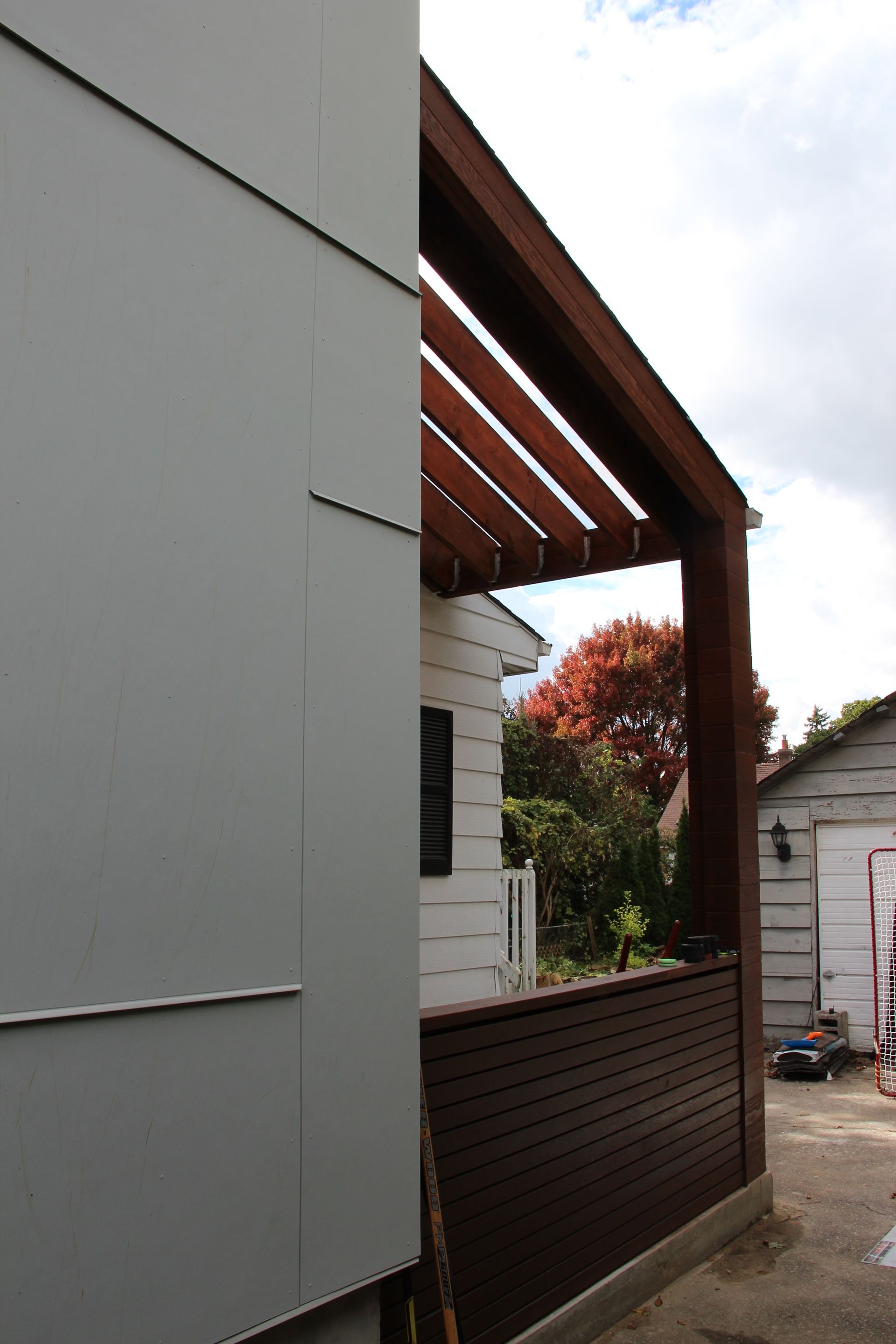 A white house with a wooden pergola on the side