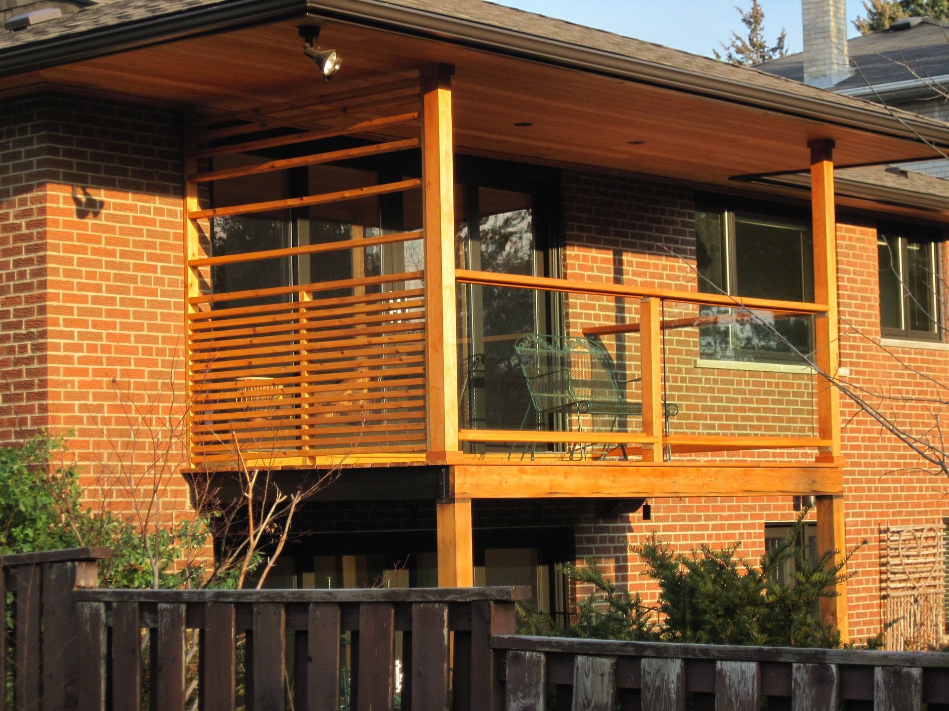 A brick house with a wooden balcony behind a wooden fence