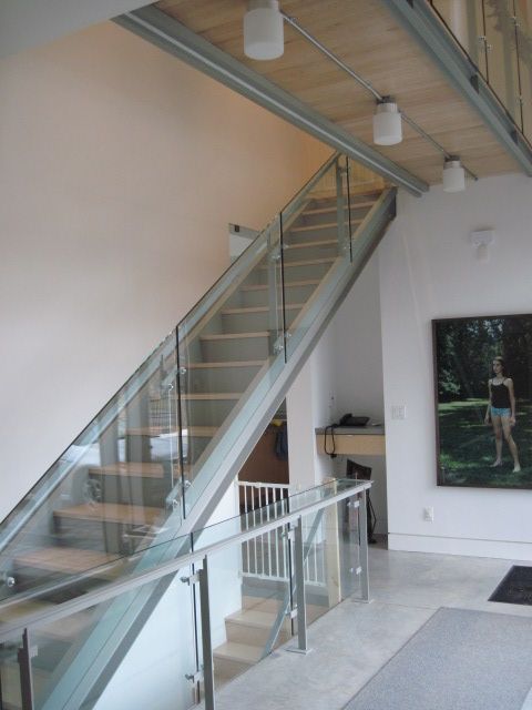 A staircase with a glass railing and a picture on the wall