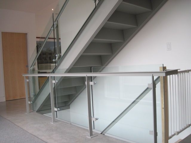 A staircase with a glass railing and a wooden door