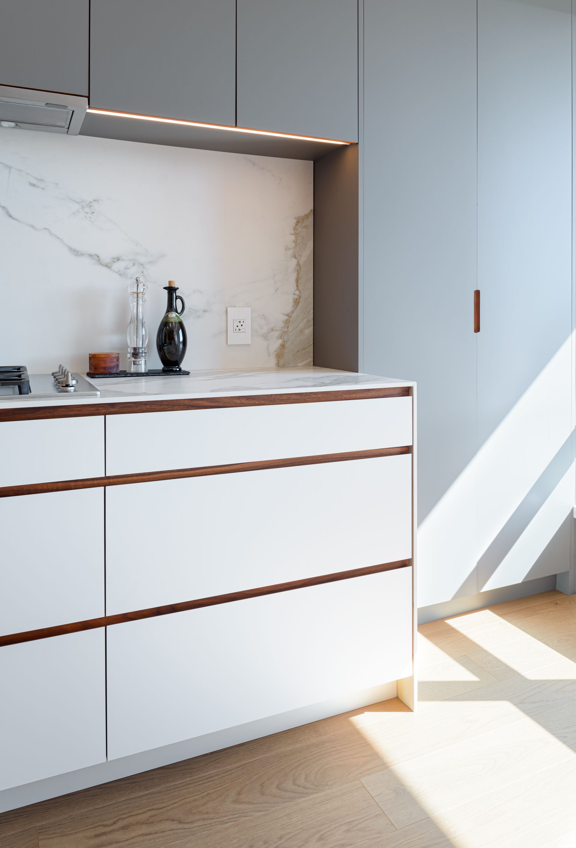 A kitchen with white cabinets and a marble counter top.