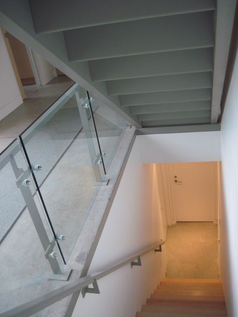 A staircase with a glass railing leading to a hallway