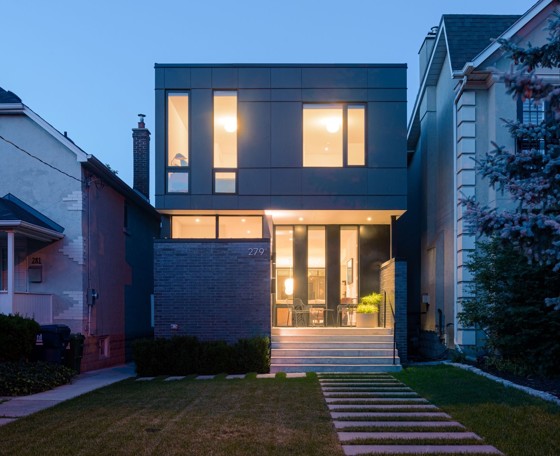 A modern house with a lot of windows and trees in front of it.