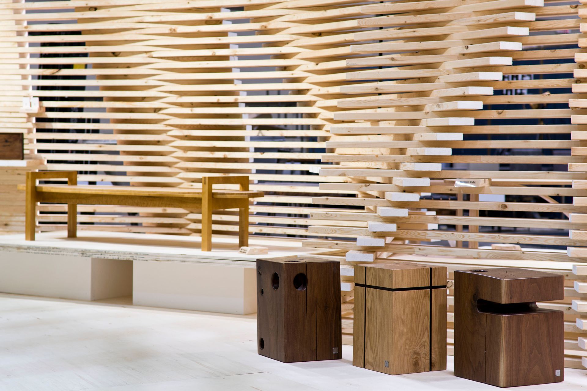 Three wooden stools are sitting in front of a wooden wall