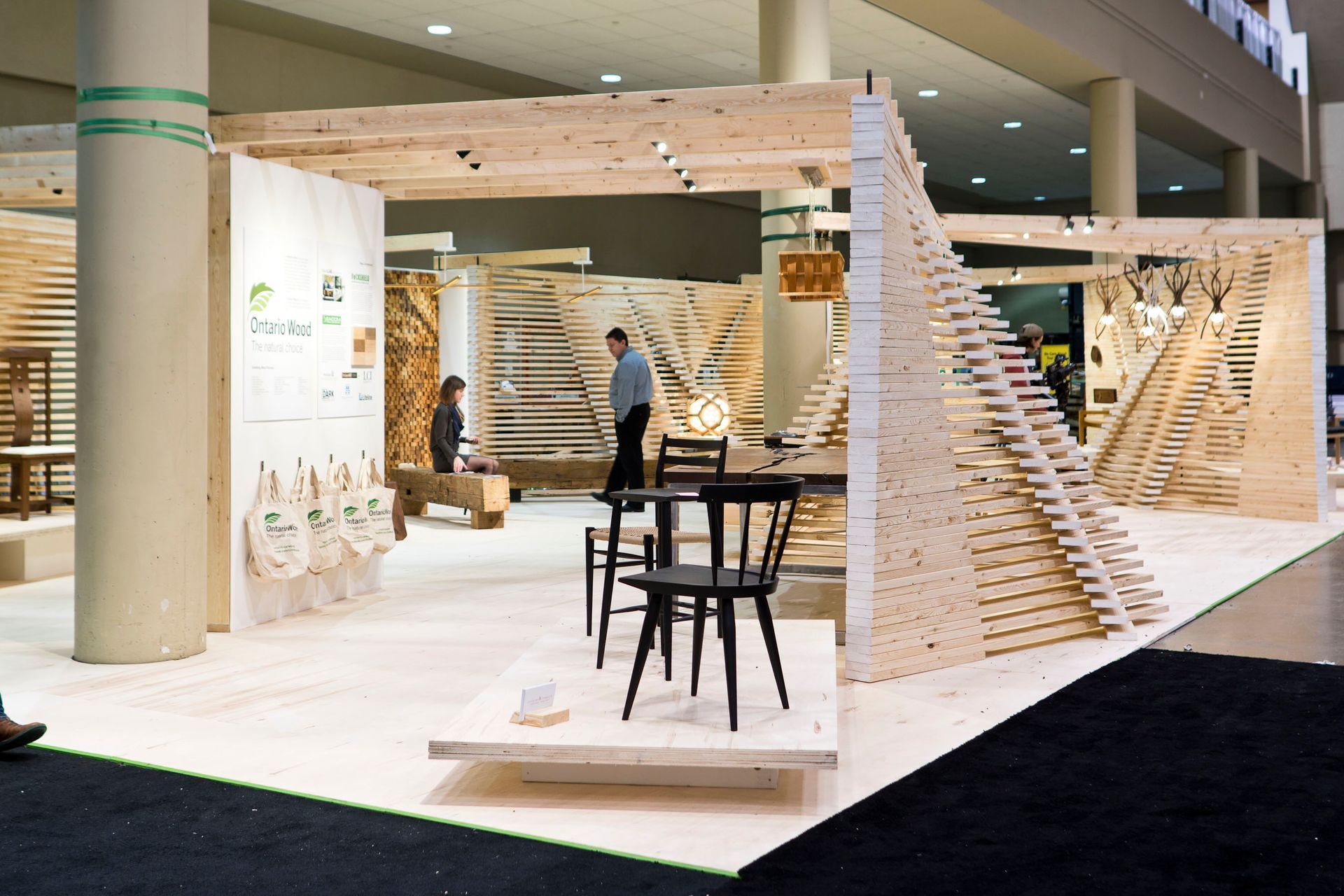 A man is standing in a room with a wooden structure and chairs