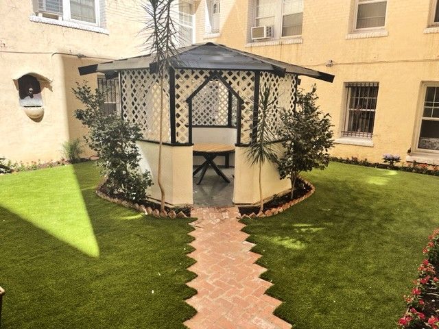 Gazebo in a small courtyard with brick path and green lawn.