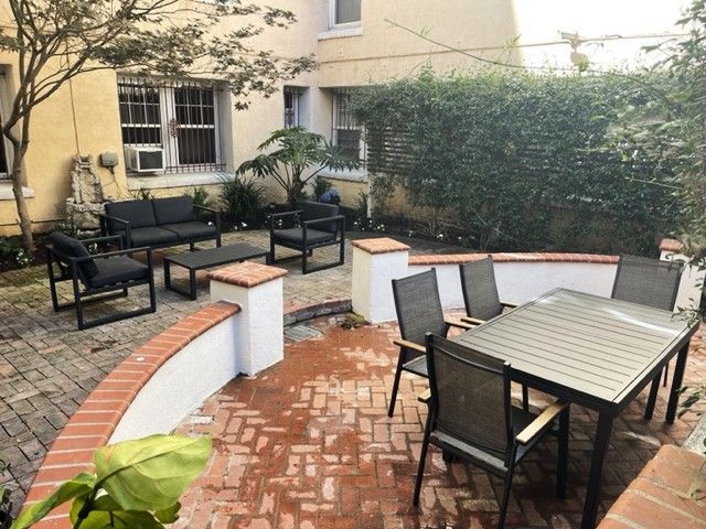 Outdoor patio with brick and white accents, seating areas, and a dining table.