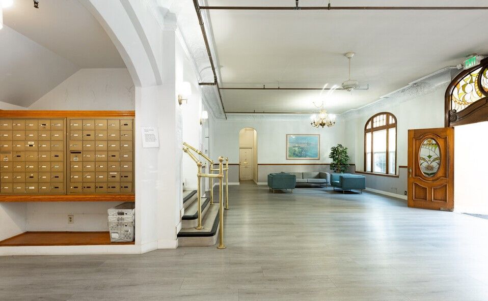 Apartment building lobby with mailboxes, seating, and a decorative wooden door.