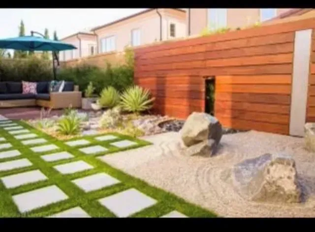 Backyard with a modern design: patio, stone path, zen garden, wooden fence, umbrella.