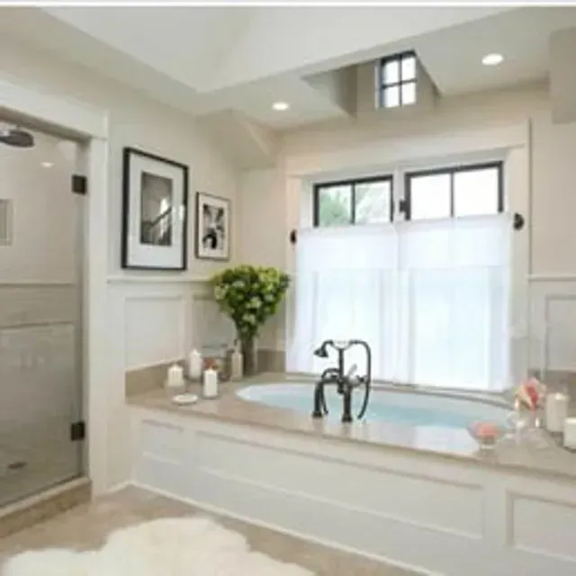 Bathroom with a white bathtub, shower, and window with white curtains.