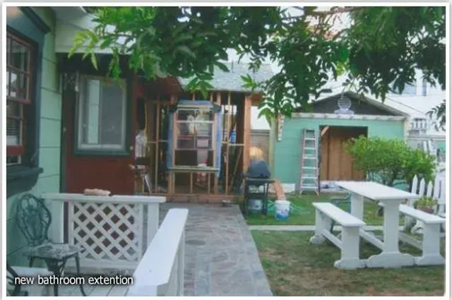 Backyard with construction: bathroom extension, shed, picnic table, and walkway.
