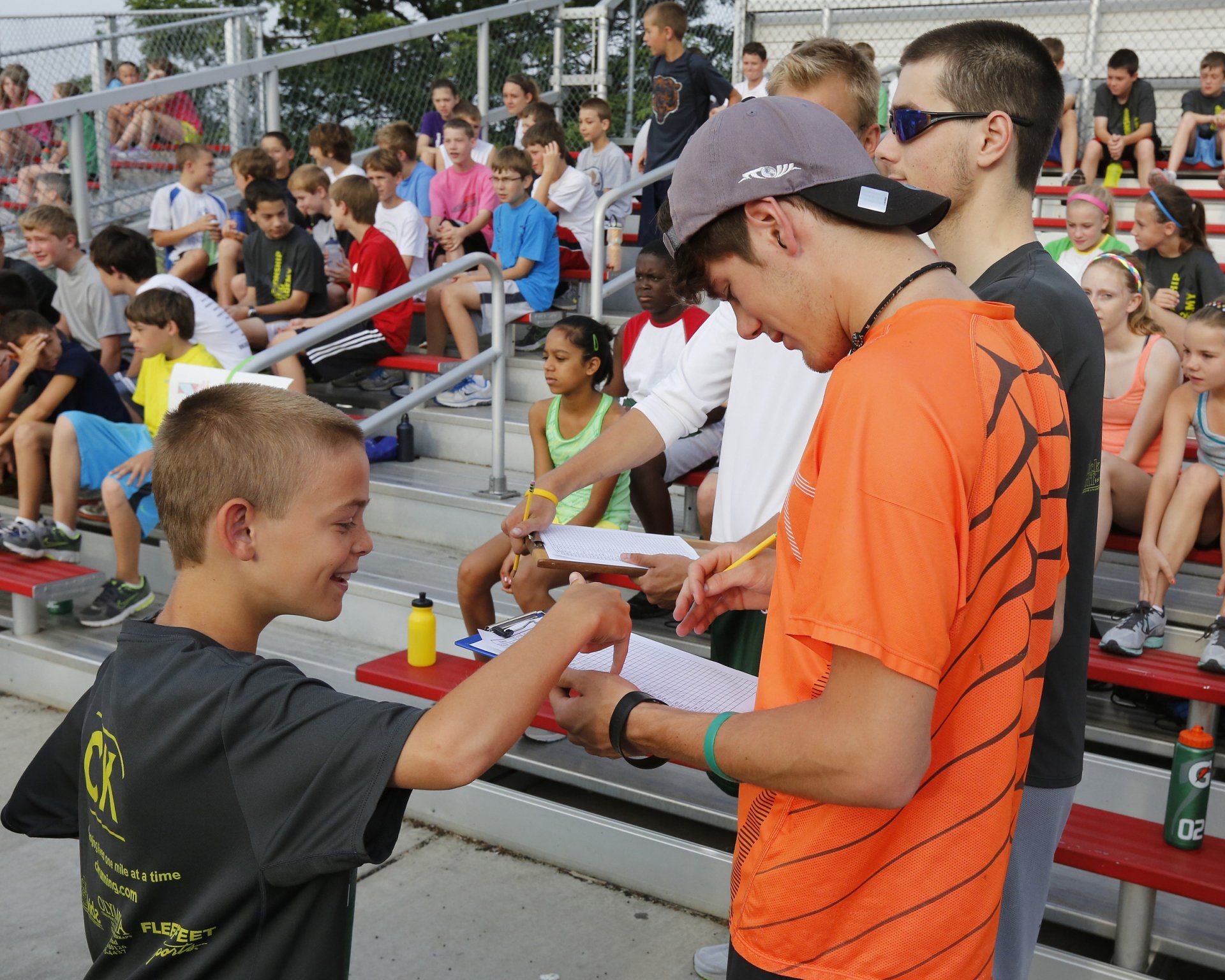 A man in an orange shirt is talking to a boy in a gray shirt