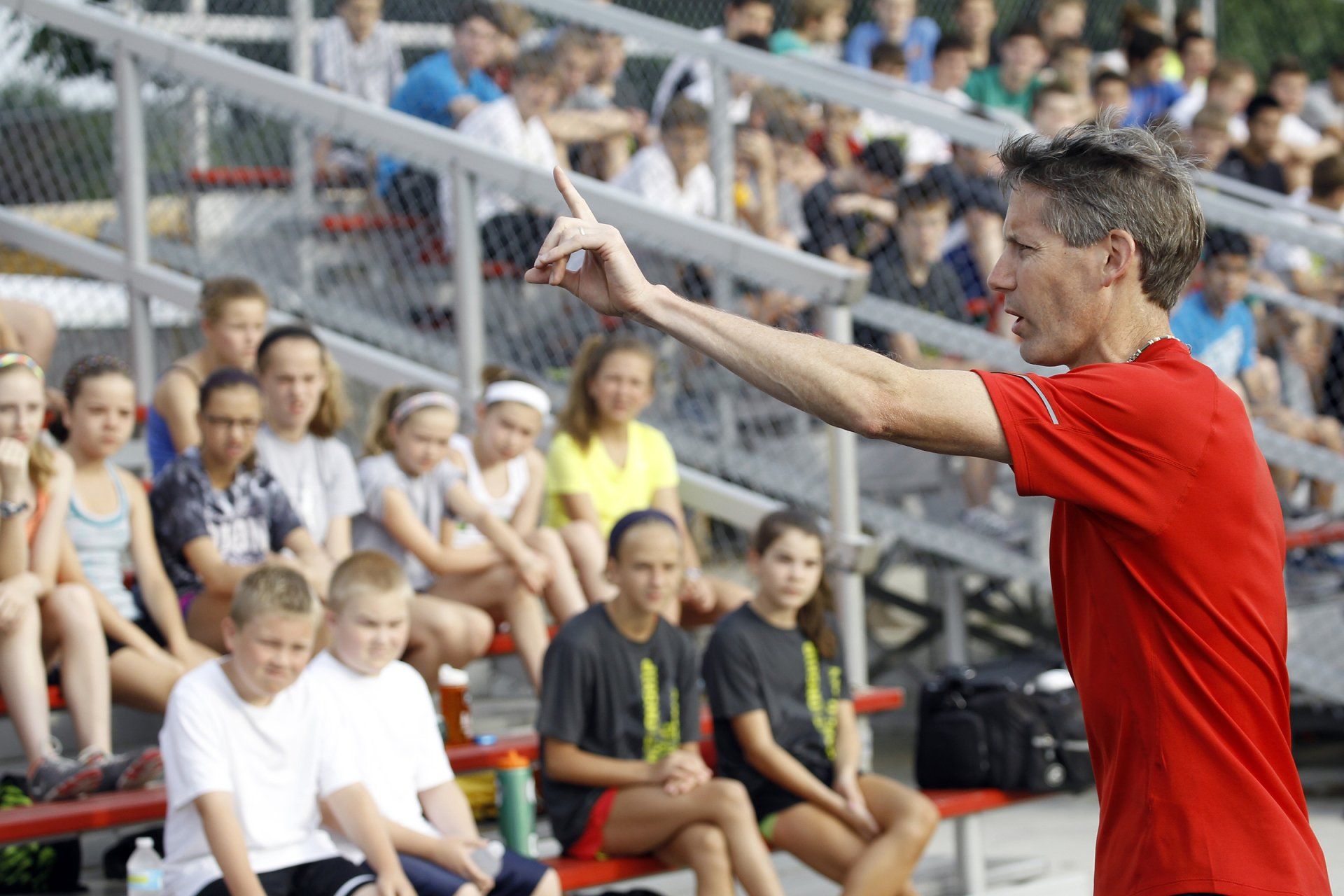 A man in a red shirt is standing in front of a crowd of people.