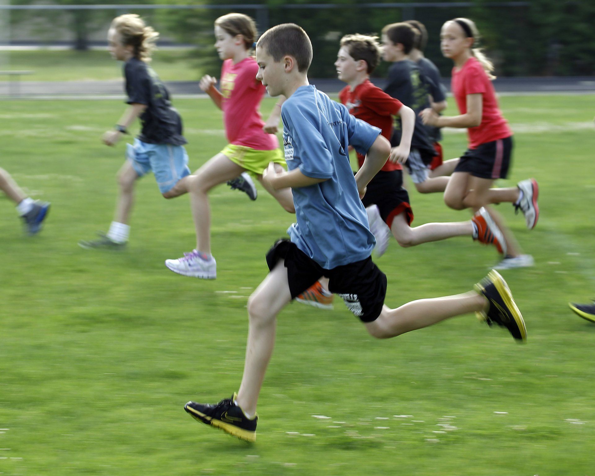 A group of children are running on a grassy field