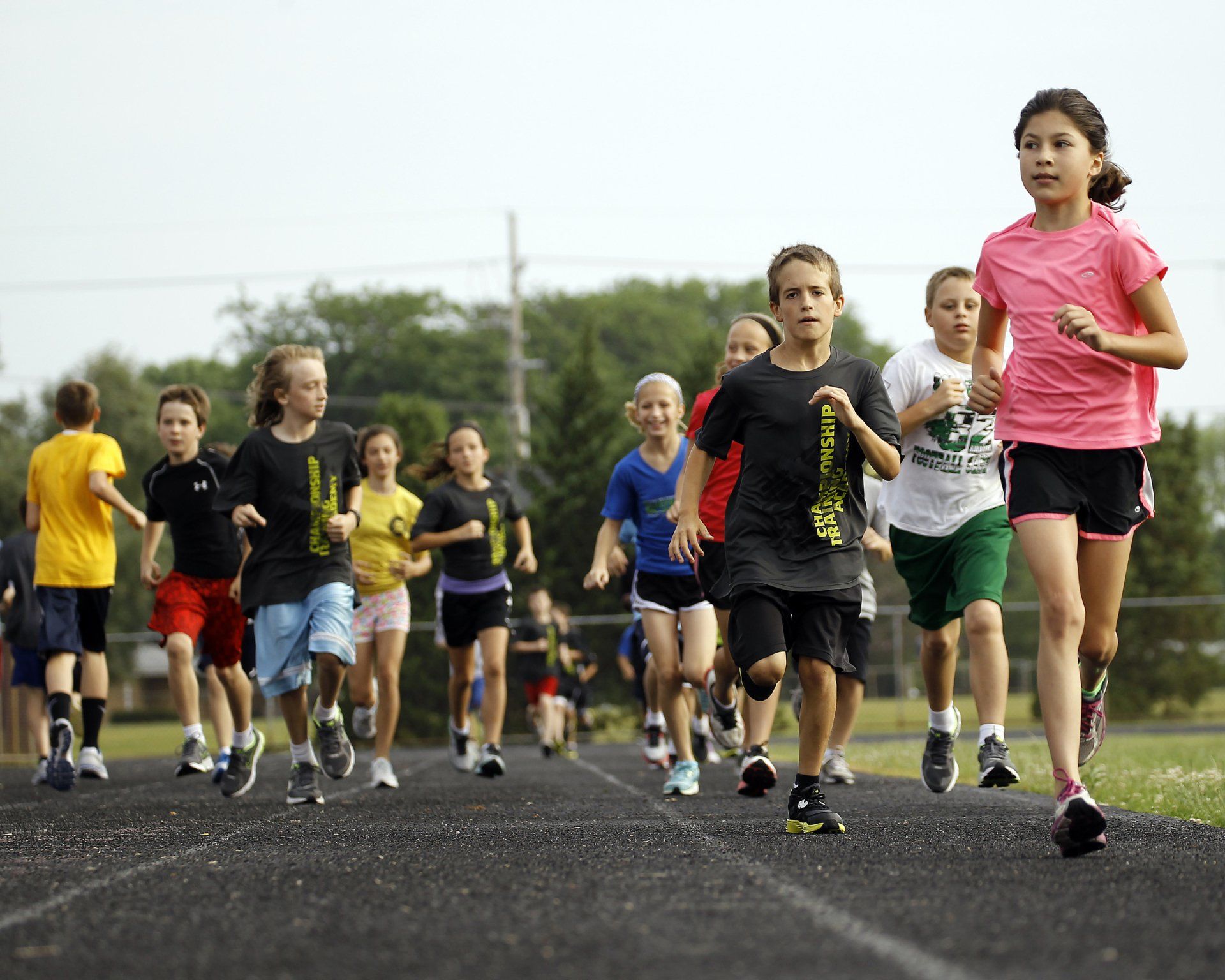 A group of children are running on a track.