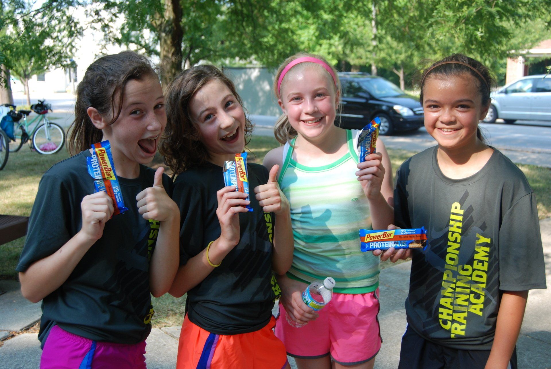A group of young girls are standing next to each other holding candy bars.