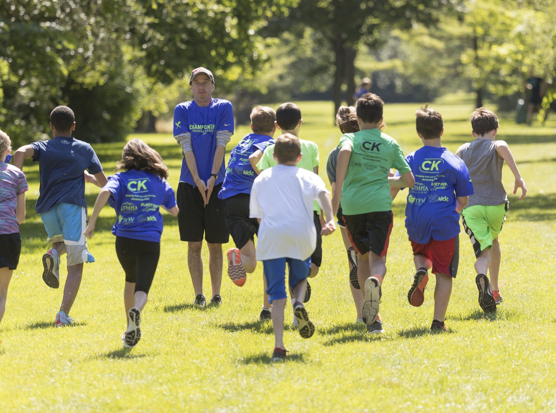 A group of children wearing ck shirts are running in a park